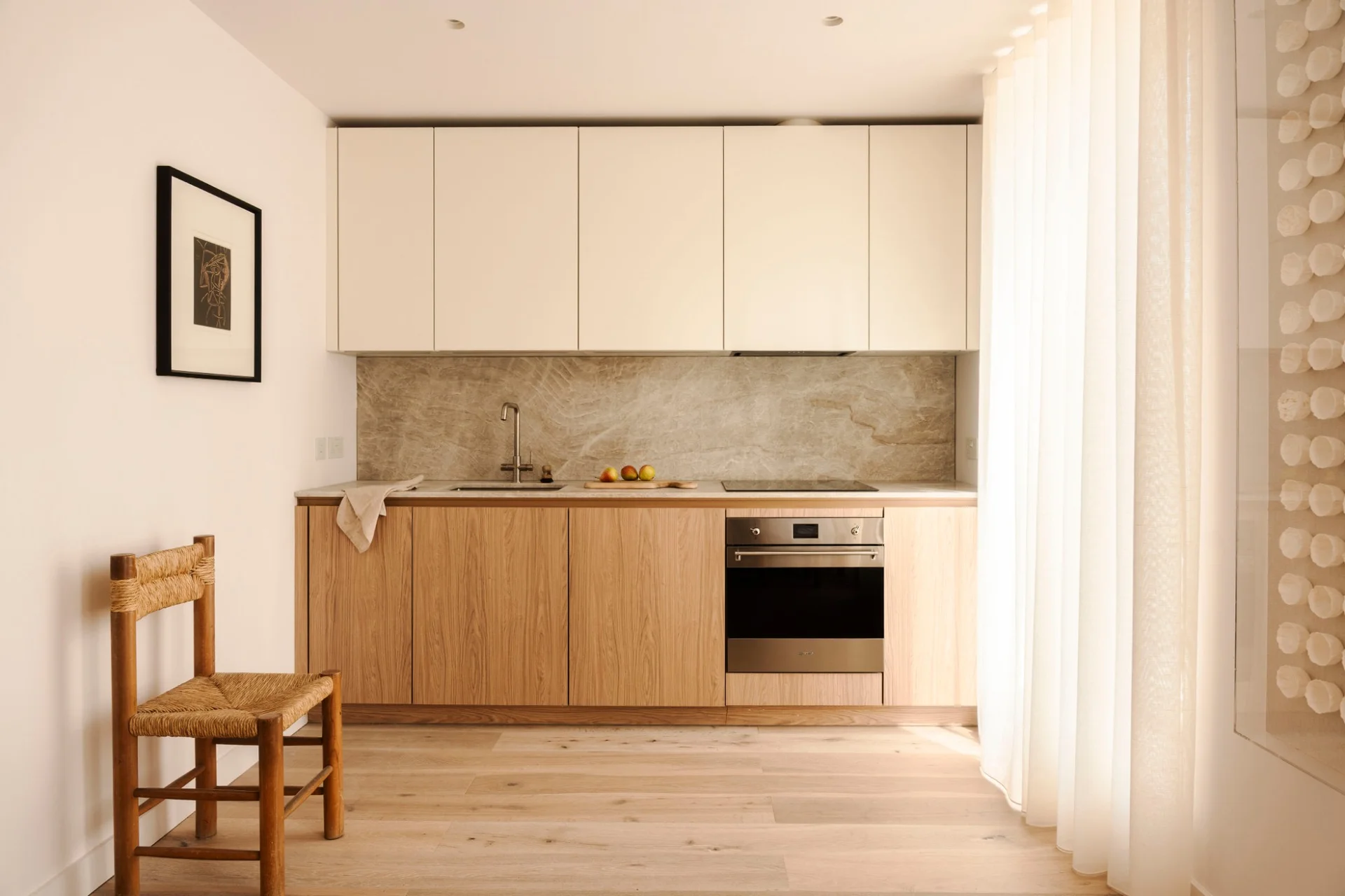 Oak kitchen with cream upper cabinets and a natural stone splashback